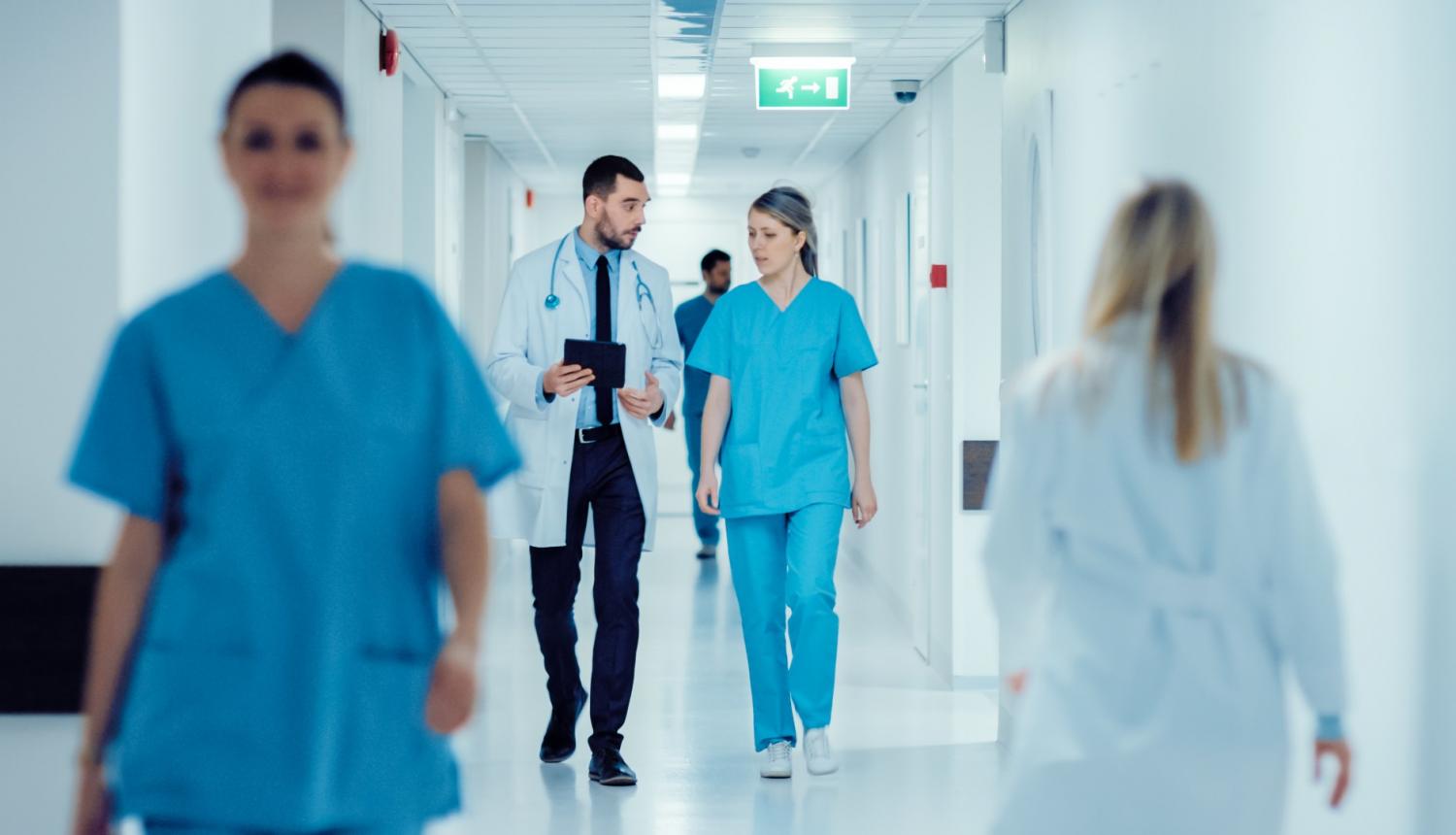 Foto: Ārsti iet pa slimnīcas koridoru 